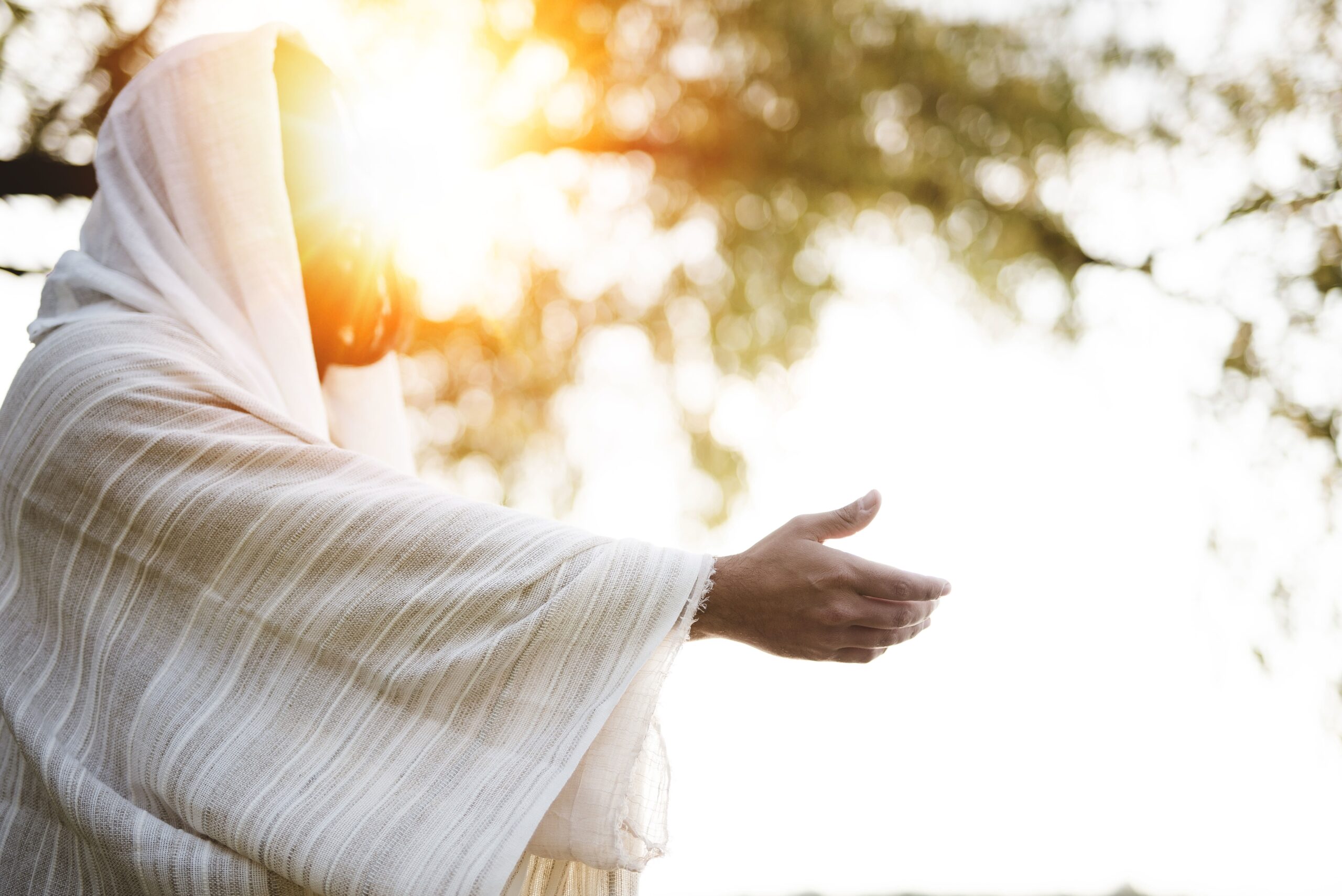 A biblical scene - of Jesus Christ landing a hand for help with the sun shining near his face